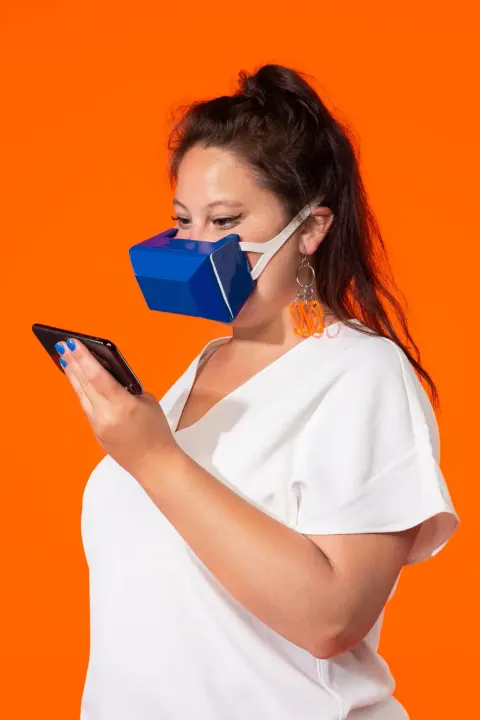 Wearing Akrasia’s blue mask while typing on a phone