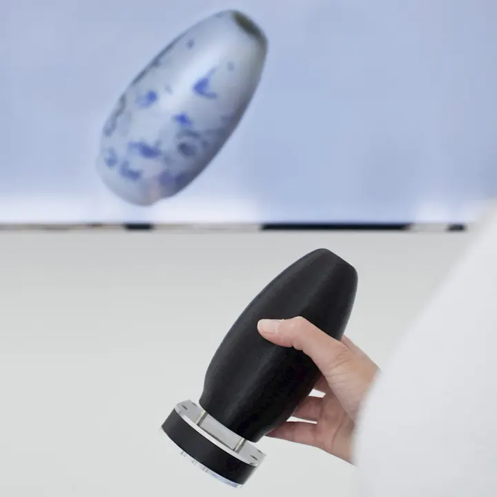 A hand turns a black replica of Martin Hyde’s True Blue vase; on the screen, the scanned vase turns with it